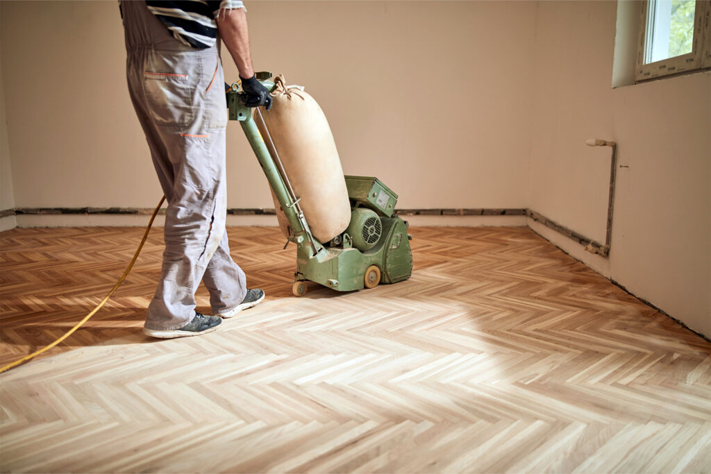 someone refinishing chevron hardwood flooring