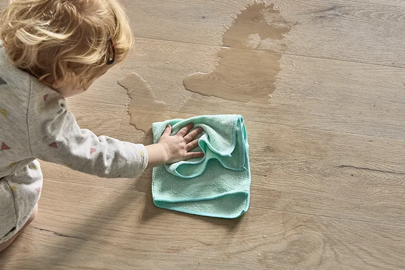 Vinyl-Moisture-Defense Child cleaning up water he spilled on vinyl with moisture defense